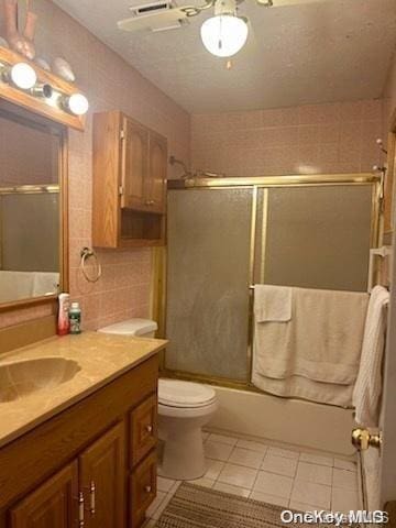 full bathroom with vanity, tile patterned floors, toilet, enclosed tub / shower combo, and tile walls