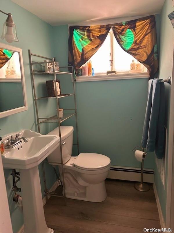 bathroom with sink, toilet, a baseboard radiator, and wood-type flooring