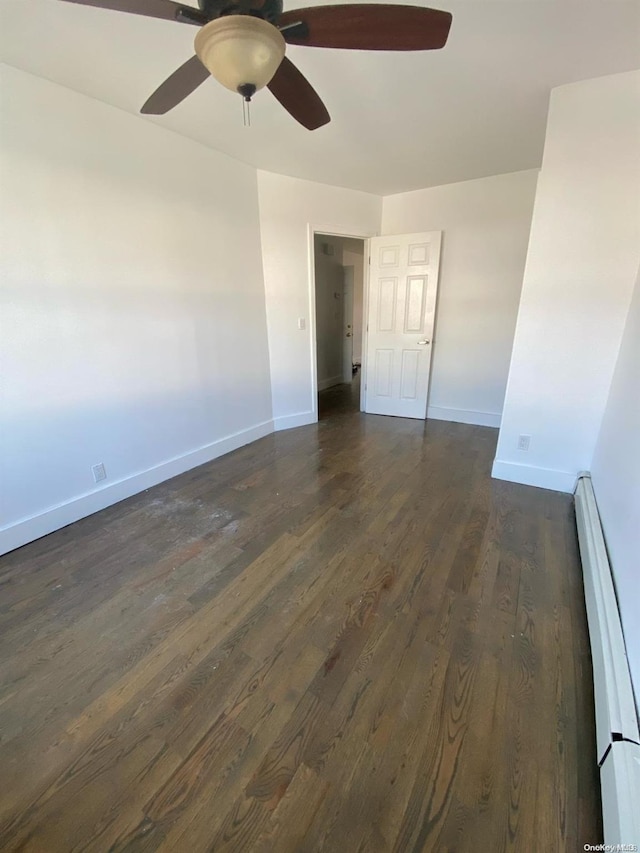 empty room with dark hardwood / wood-style floors, ceiling fan, and baseboard heating