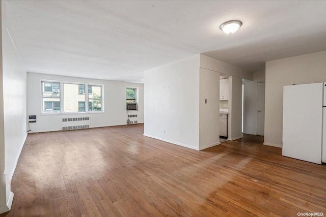 empty room with light wood-type flooring and radiator