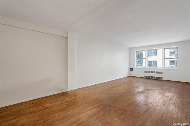 empty room featuring wood-type flooring and radiator