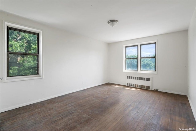 empty room featuring radiator, dark hardwood / wood-style flooring, and a healthy amount of sunlight