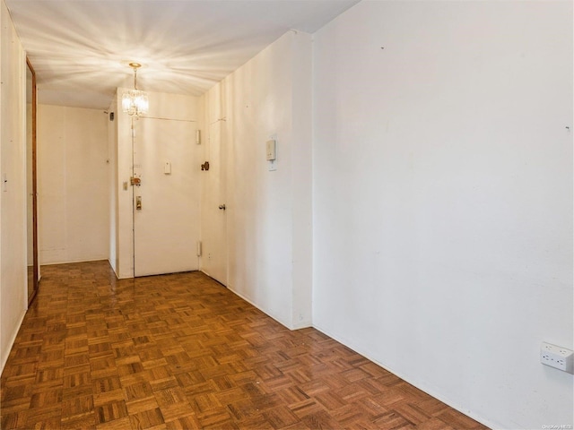 corridor with dark parquet floors and an inviting chandelier