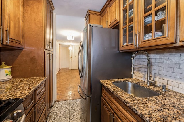 kitchen featuring appliances with stainless steel finishes, backsplash, sink, and dark stone counters