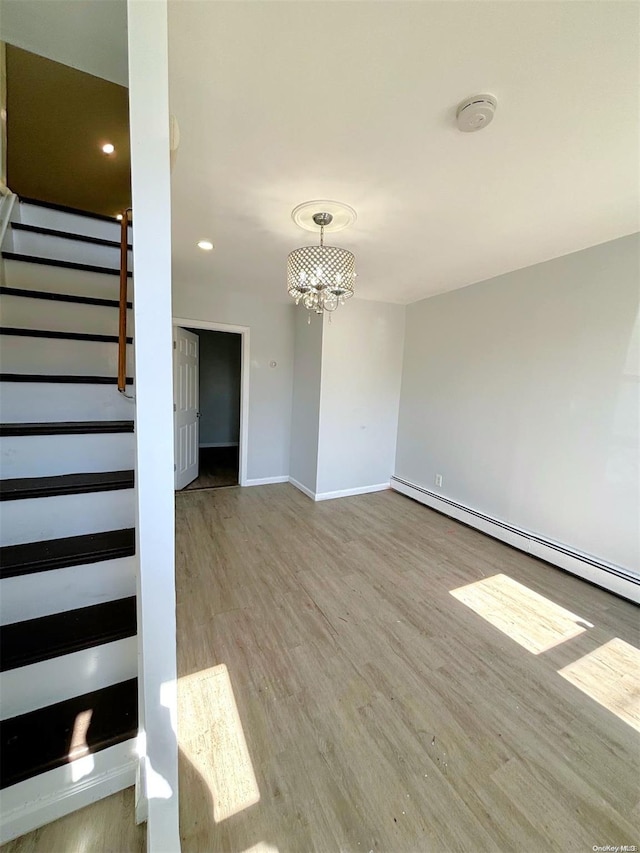 interior space featuring a notable chandelier, light wood-type flooring, and a baseboard heating unit