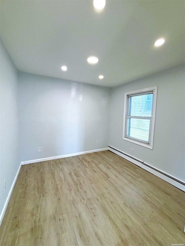 spare room featuring a baseboard radiator and light wood-type flooring