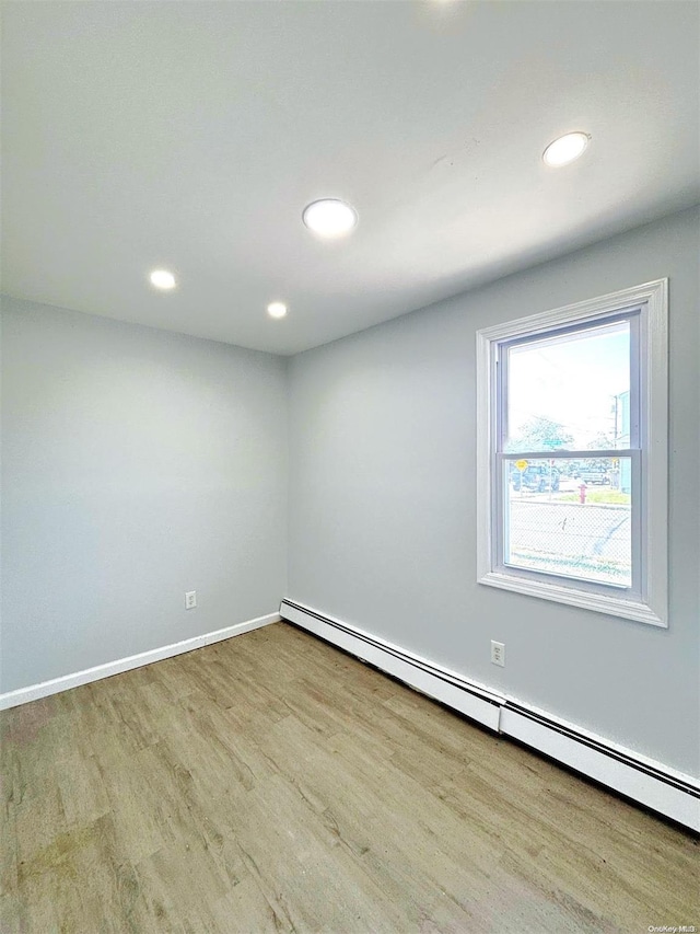 empty room featuring a baseboard radiator and light hardwood / wood-style floors