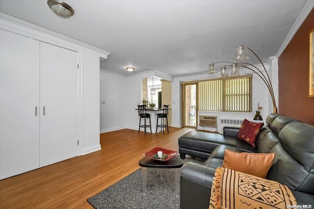 living room featuring wood-type flooring, a wall unit AC, radiator, and ornamental molding