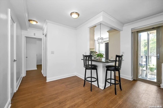 dining area featuring ornamental molding, dark wood-type flooring, and a chandelier