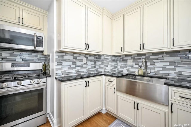 kitchen with decorative backsplash, sink, appliances with stainless steel finishes, and cream cabinets