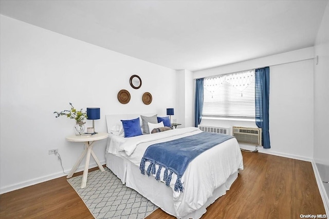 bedroom with radiator, a wall mounted AC, and hardwood / wood-style flooring