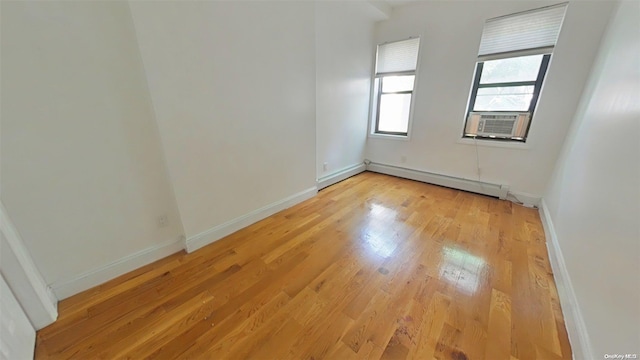 spare room with cooling unit, light hardwood / wood-style floors, and a baseboard heating unit