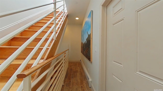 staircase featuring wood-type flooring and baseboard heating