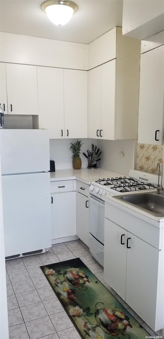 kitchen featuring white cabinets, white refrigerator, light tile patterned flooring, and sink