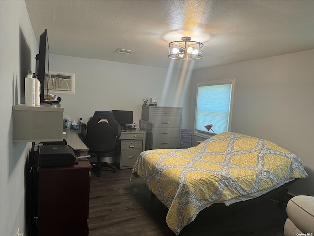 bedroom with an AC wall unit, dark hardwood / wood-style flooring, and a textured ceiling