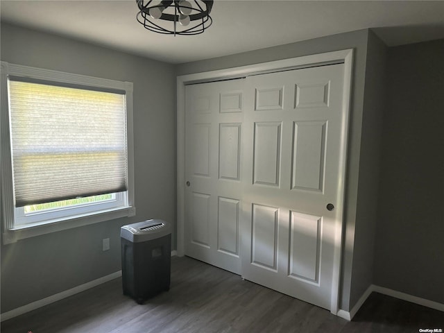 unfurnished bedroom featuring a closet, dark wood-type flooring, and an inviting chandelier