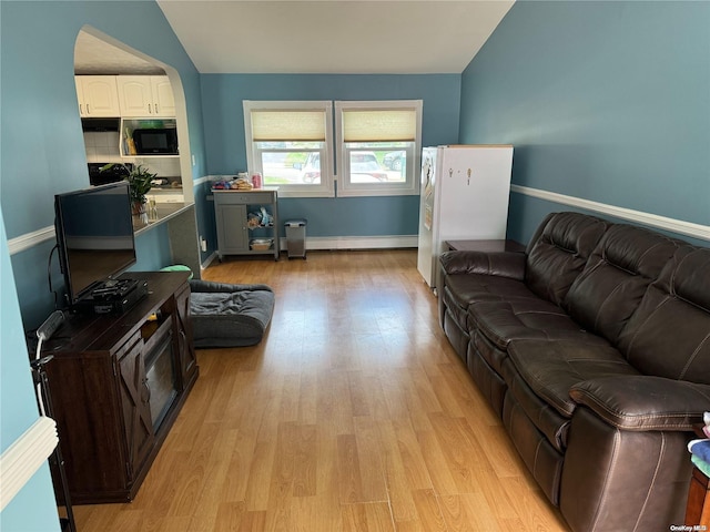 living room with a baseboard heating unit, vaulted ceiling, and light hardwood / wood-style flooring