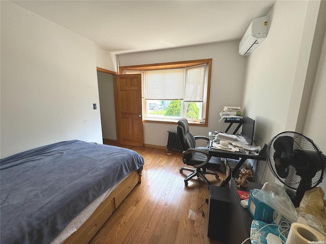 bedroom featuring a wall unit AC and light wood-type flooring