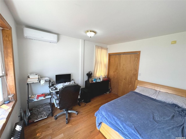 bedroom featuring hardwood / wood-style flooring, an AC wall unit, and a closet