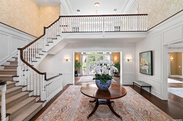 foyer entrance with a towering ceiling, dark wood-type flooring, and ornamental molding