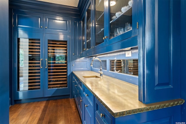 bar featuring blue cabinetry, dark wood-type flooring, and sink