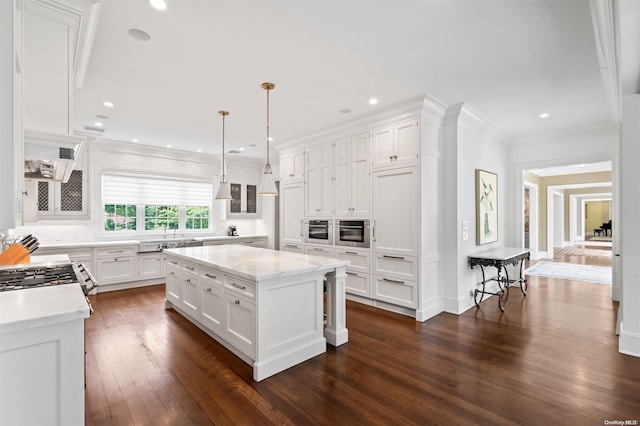 kitchen with a center island, dark wood-type flooring, ornamental molding, decorative light fixtures, and white cabinetry