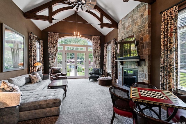 carpeted living room featuring french doors, high vaulted ceiling, beamed ceiling, a fireplace, and ceiling fan with notable chandelier