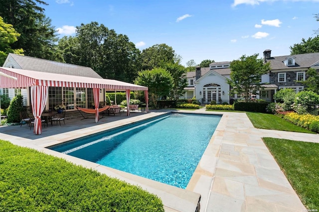 view of swimming pool featuring an outbuilding, a yard, and a patio