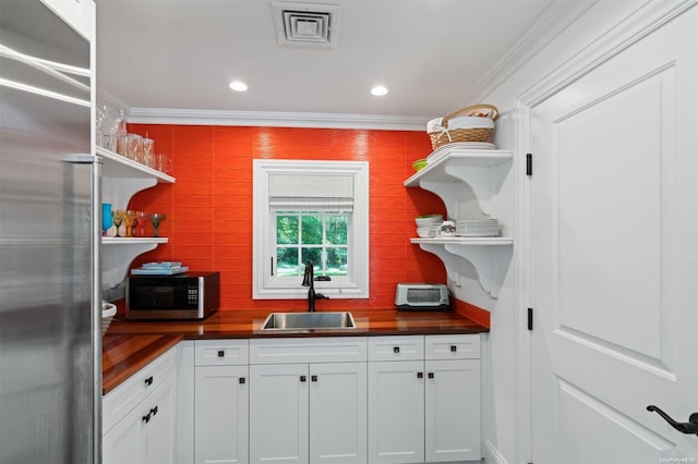 kitchen with sink, stainless steel appliances, backsplash, crown molding, and white cabinets