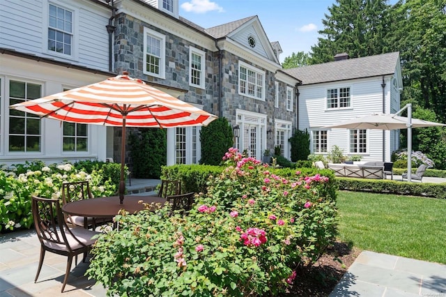 back of property with a yard and a patio