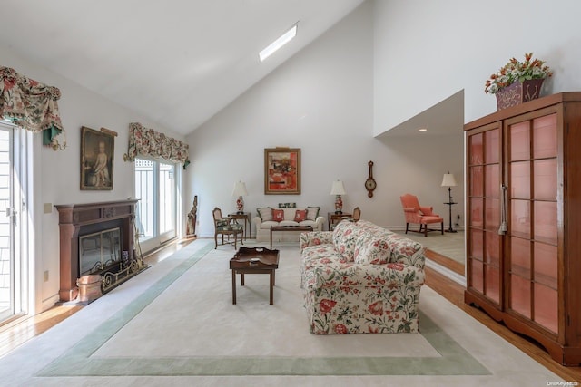 living room with light hardwood / wood-style floors, high vaulted ceiling, and a skylight