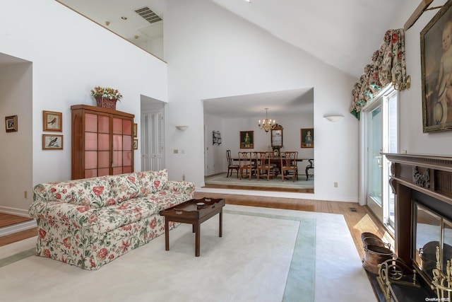 living room with a chandelier, light wood-type flooring, and high vaulted ceiling