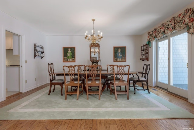 dining space featuring light hardwood / wood-style floors and an inviting chandelier