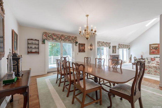 dining space with a healthy amount of sunlight, an inviting chandelier, lofted ceiling, and light hardwood / wood-style flooring