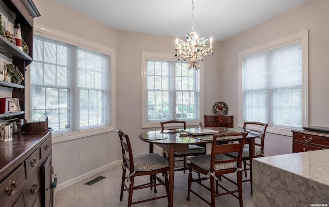 dining area with a healthy amount of sunlight, a notable chandelier, and light wood-type flooring