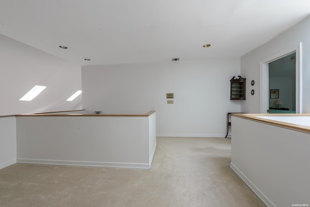 hallway featuring light carpet and vaulted ceiling with skylight