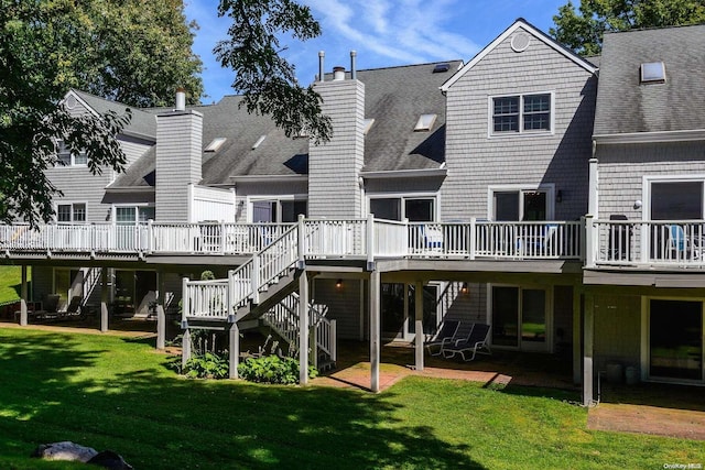 rear view of house with a lawn, a deck, and a patio