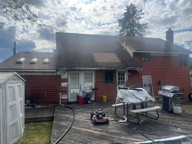 back of property with a wooden deck, french doors, and a storage shed