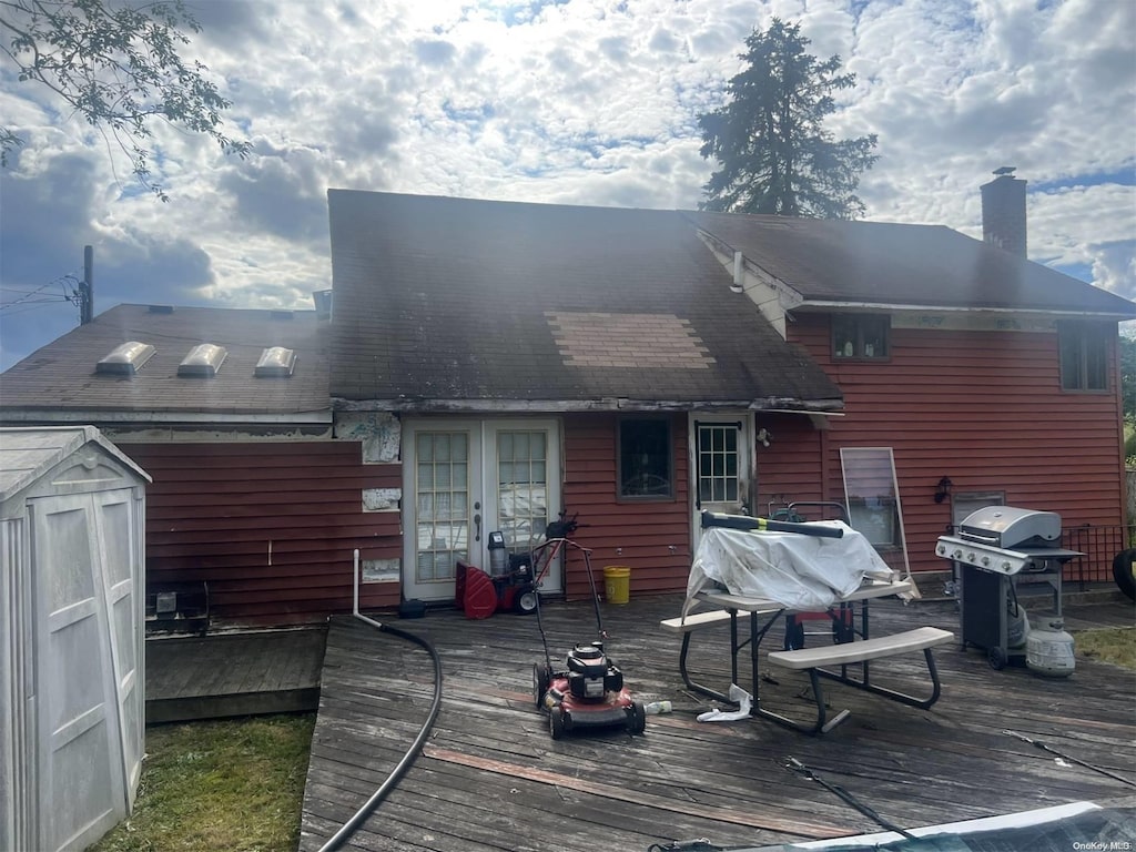 rear view of house featuring a wooden deck, a shed, and a chimney