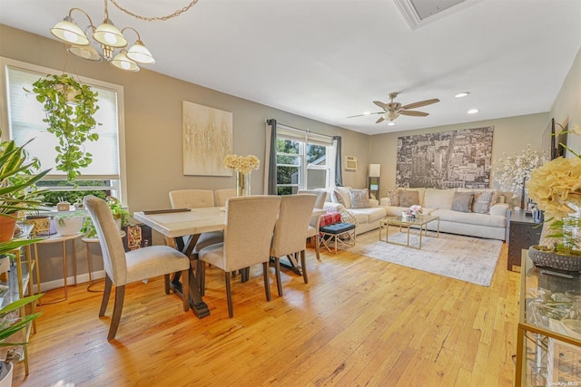 dining space featuring ceiling fan with notable chandelier and light wood-type flooring