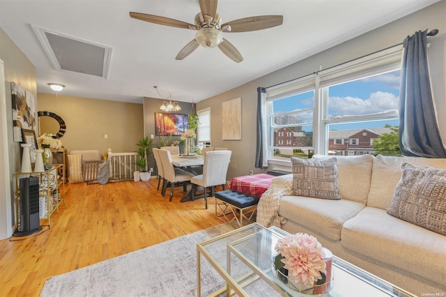 living room featuring ceiling fan with notable chandelier and hardwood / wood-style flooring