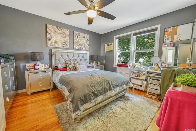 bedroom featuring ceiling fan, a wall unit AC, and light hardwood / wood-style flooring