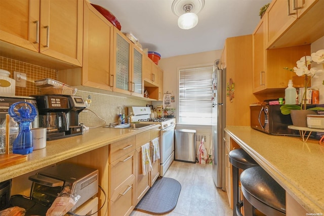 kitchen with sink, light brown cabinets, stainless steel appliances, backsplash, and light tile patterned flooring