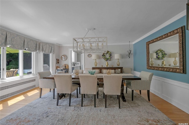 dining room with light wood-type flooring, radiator heating unit, and ornamental molding