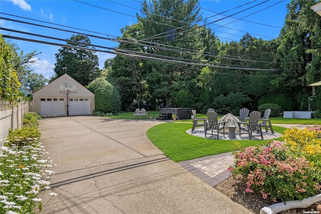 view of yard featuring a fire pit, a hot tub, a garage, an outbuilding, and a patio