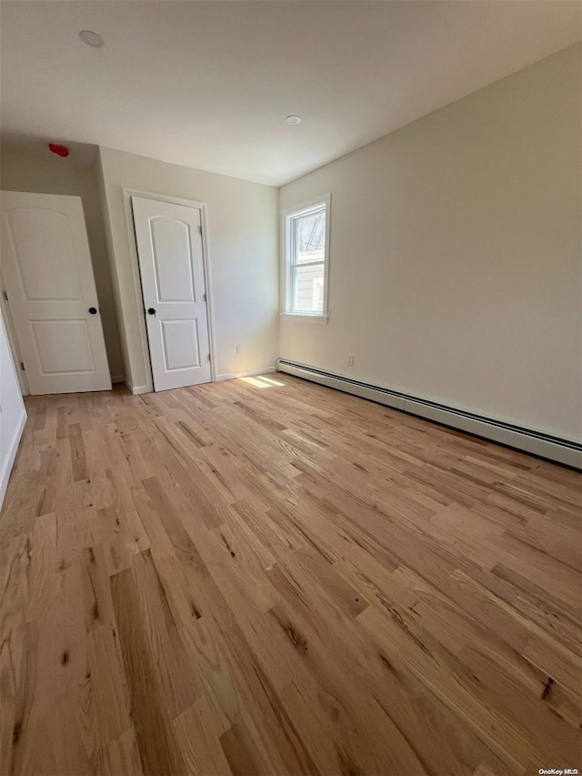 unfurnished room featuring light hardwood / wood-style floors and baseboard heating