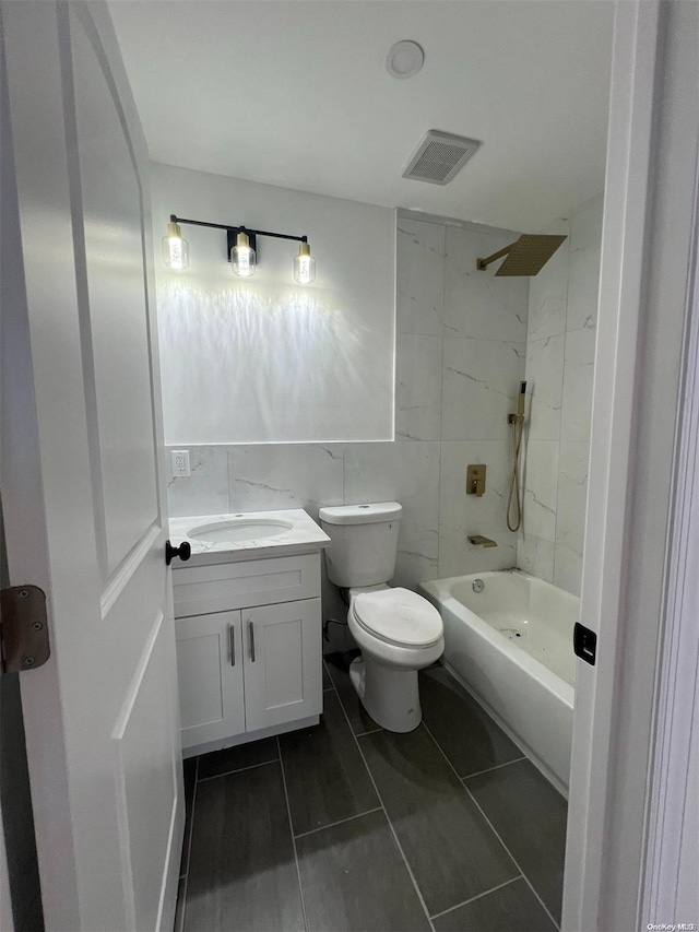 full bathroom featuring vanity, tile patterned floors, tiled shower / bath, toilet, and tile walls