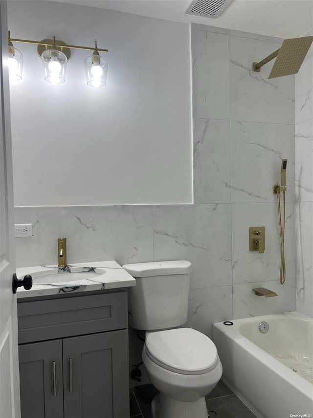 full bathroom featuring tiled shower / bath, vanity, toilet, and tile walls