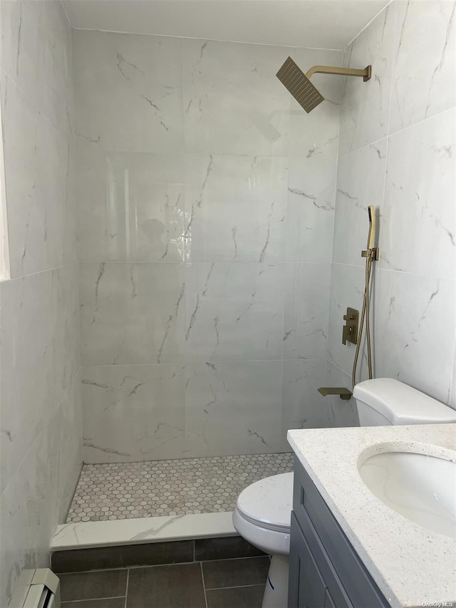 bathroom featuring vanity, tile patterned floors, toilet, a baseboard radiator, and a tile shower