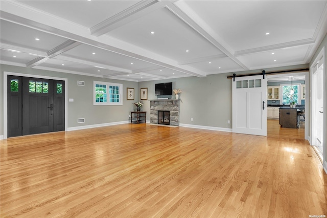 unfurnished living room featuring a barn door, light hardwood / wood-style flooring, beamed ceiling, and coffered ceiling